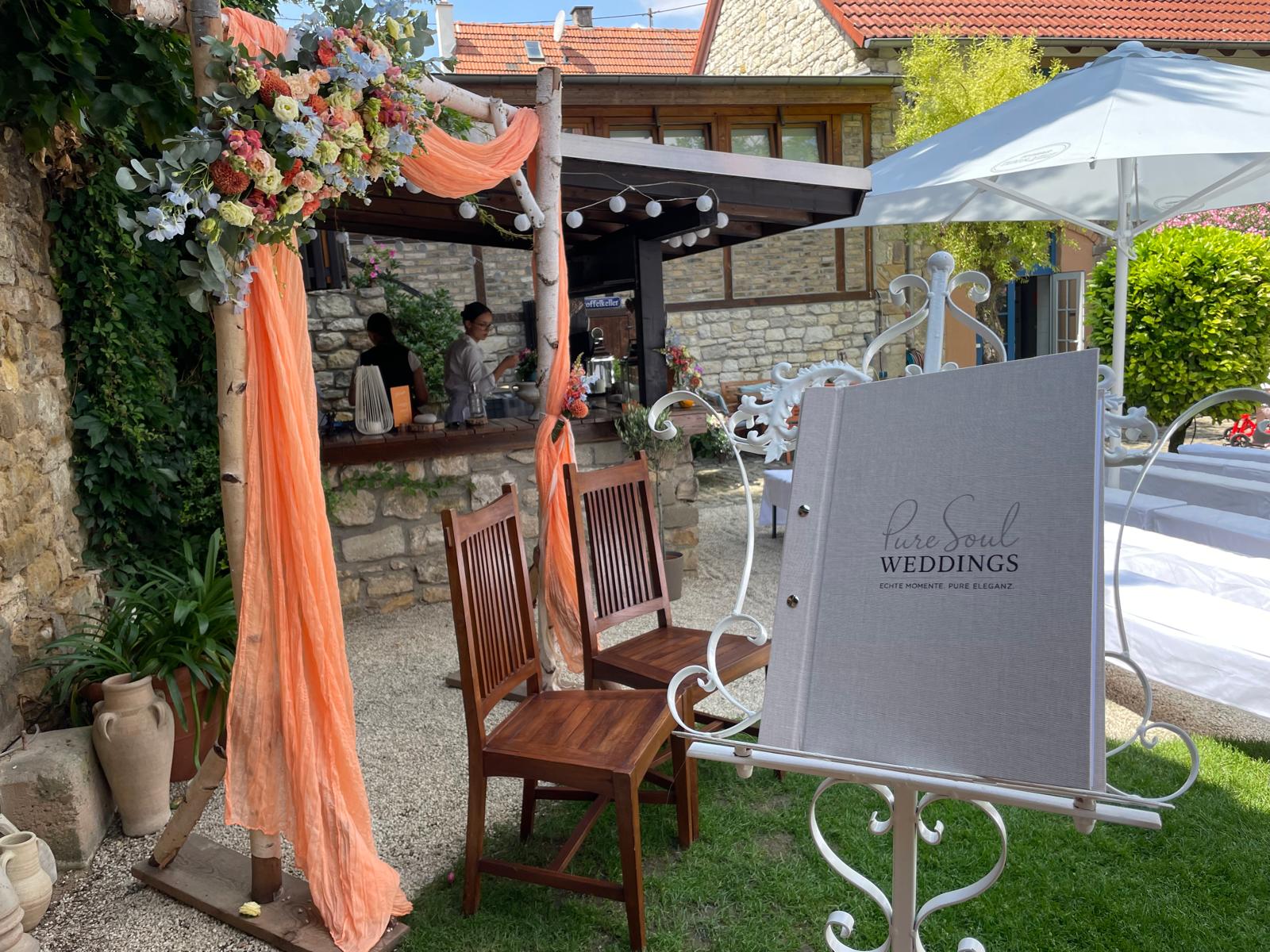 Dekorierter Traubereich für eine freie Hochzeit mit floraler Gestaltung in Orange und Pastelltönen