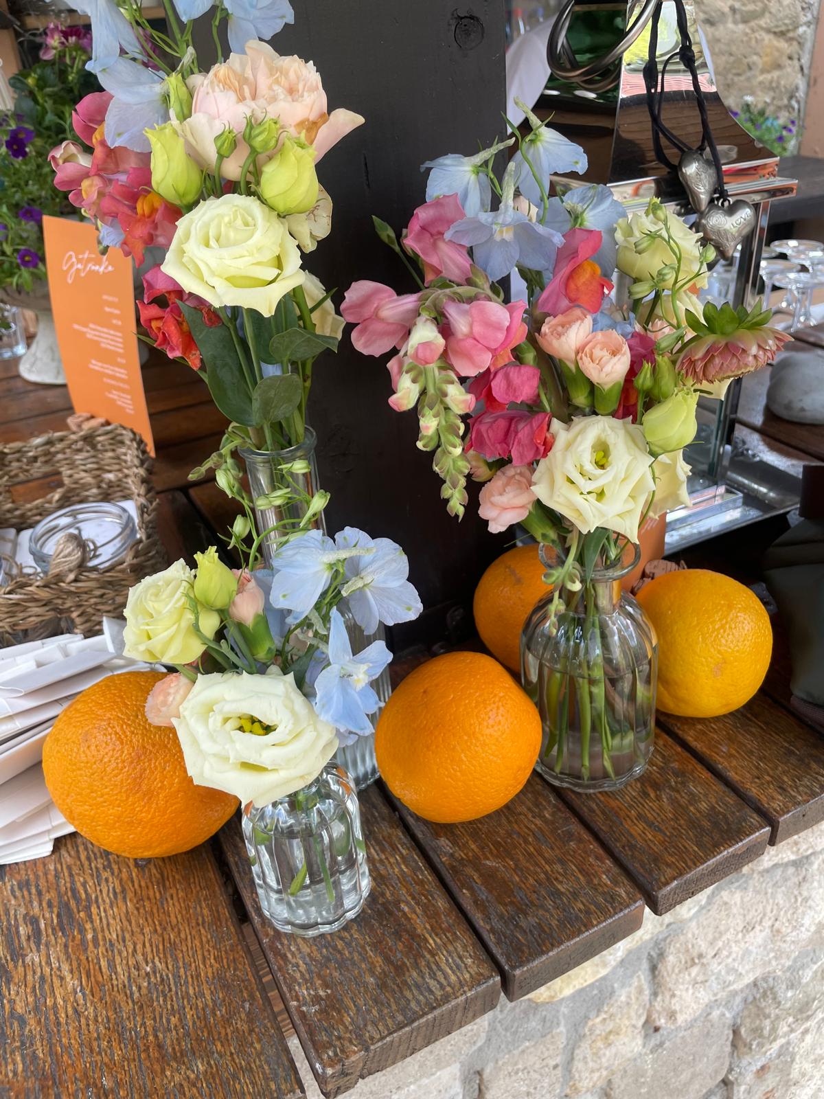 Hochzeitsfloristik in Orange, Rosa und Hellblau mit frischen Orangen als Teil des Dekorationskonzepts